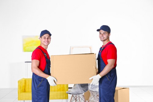Removal professionals carrying furniture down stairs in a Friern Barnet flat